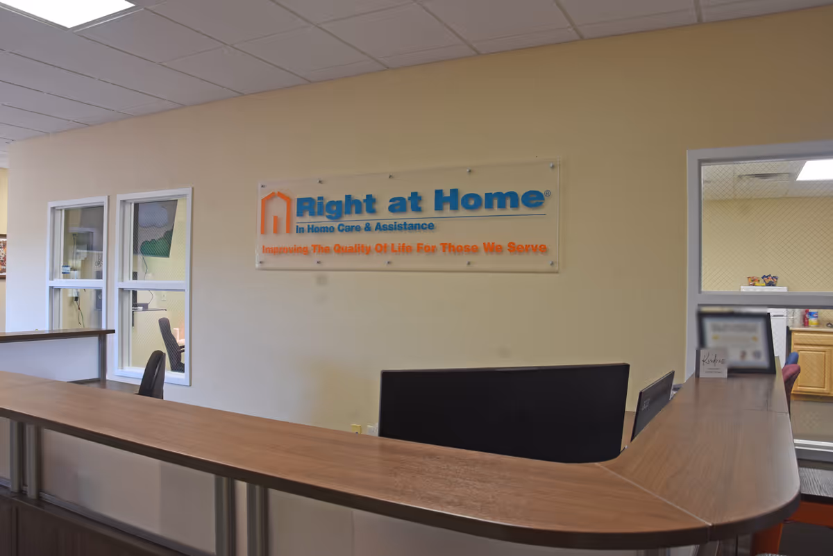 Curved wooden reception desk in beige interior with a Right at Home sign.