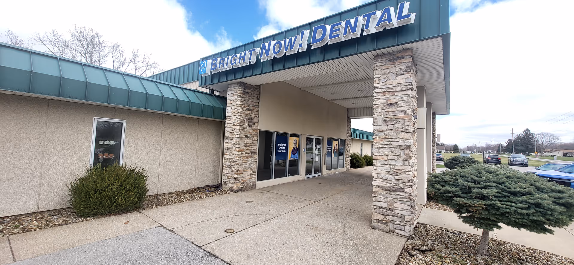 Exterior view of a dental clinic with stone pillars and blue signage.