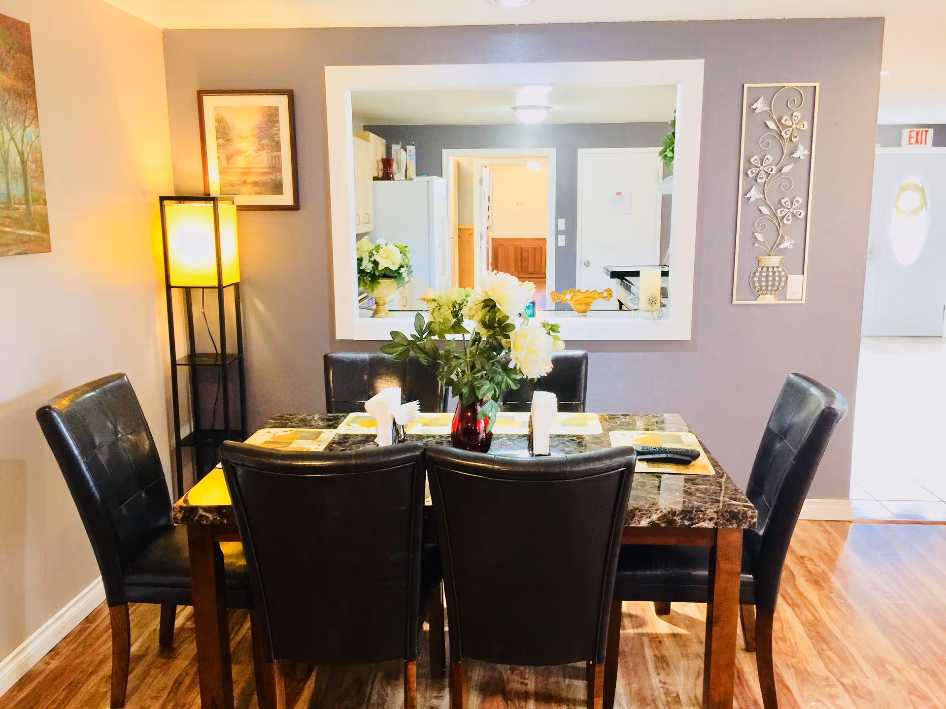 Dining area with a marble table, six black chairs, and a flower centerpiece.