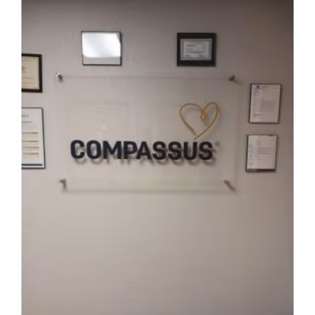 Interior wall showing a Compassus sign with framed certificates and documents around it.