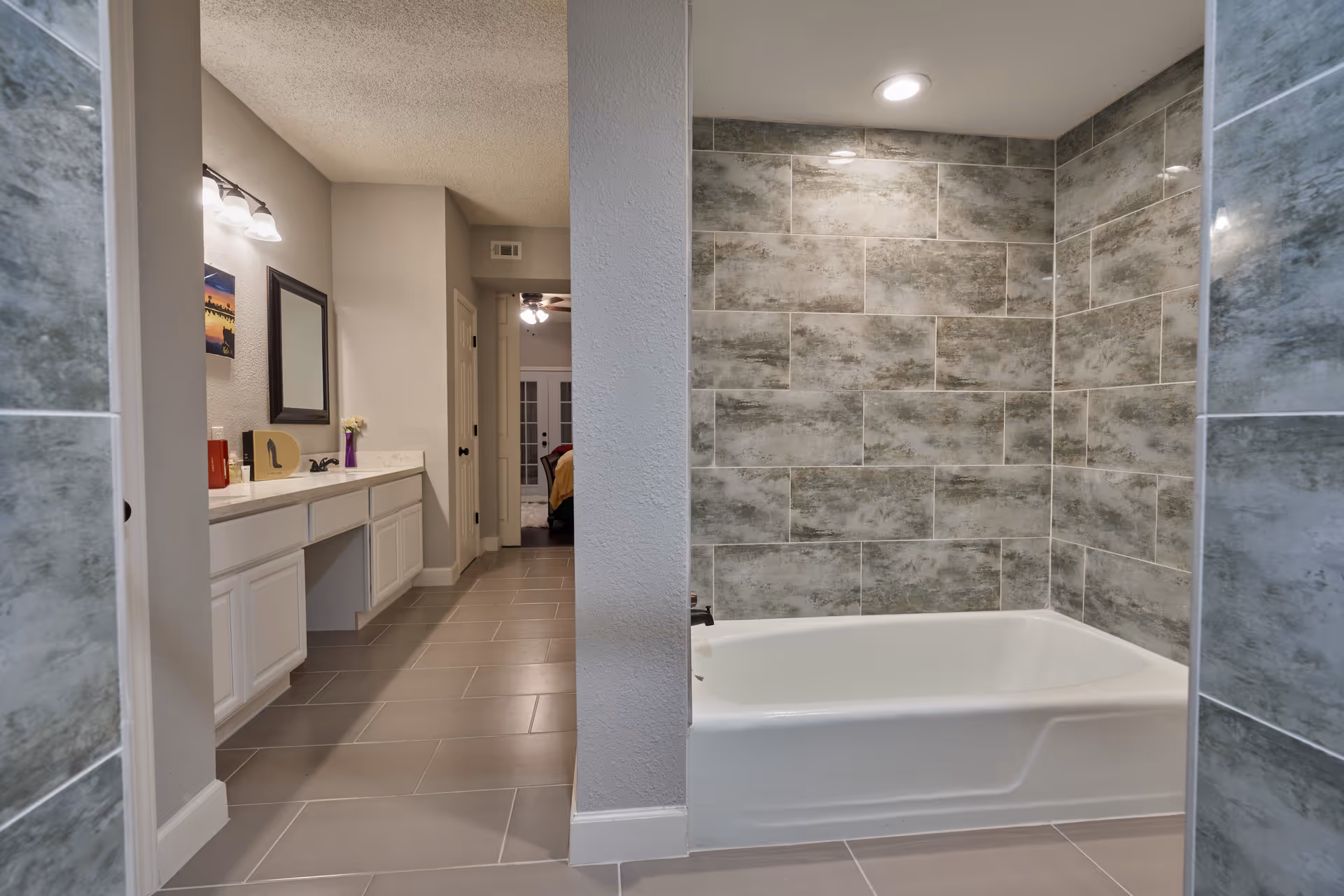 Modern bathroom with vanity, mirror, and tiled bathtub area.