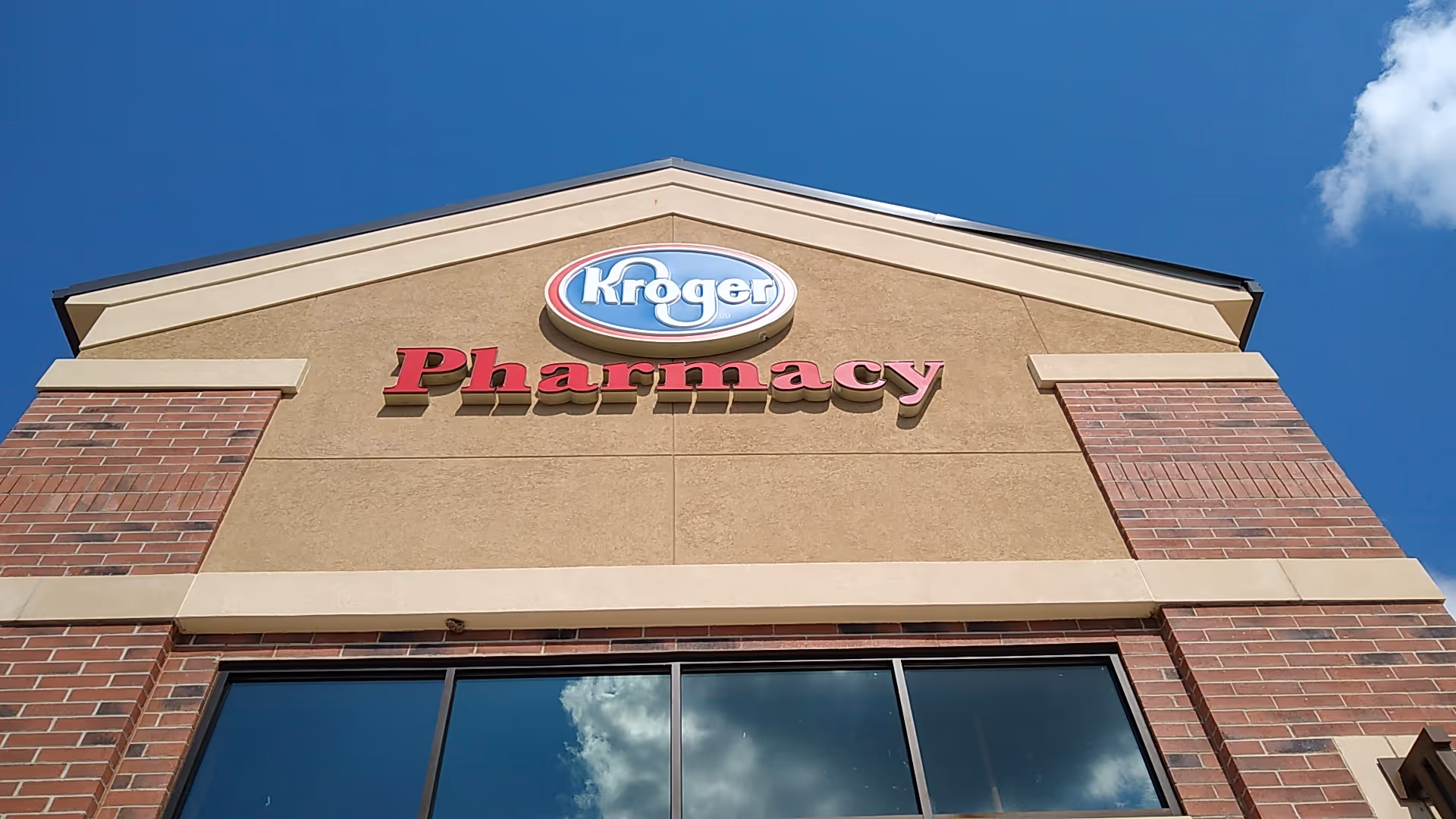 Exterior view of a Kroger Pharmacy storefront with blue sky.