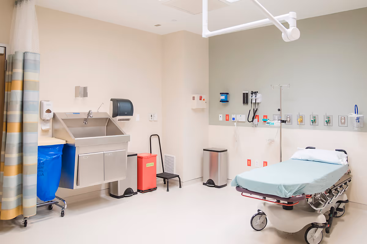 Interior hospital room with a wheeled patient bed, medical equipment, and privacy curtain.