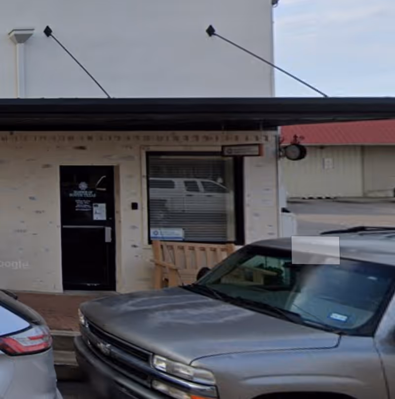 Front exterior of Hospice of South Texas building with entrance, window, and parked cars.