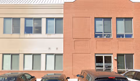 Exterior view of a two-tone brick senior care facility with parked cars.