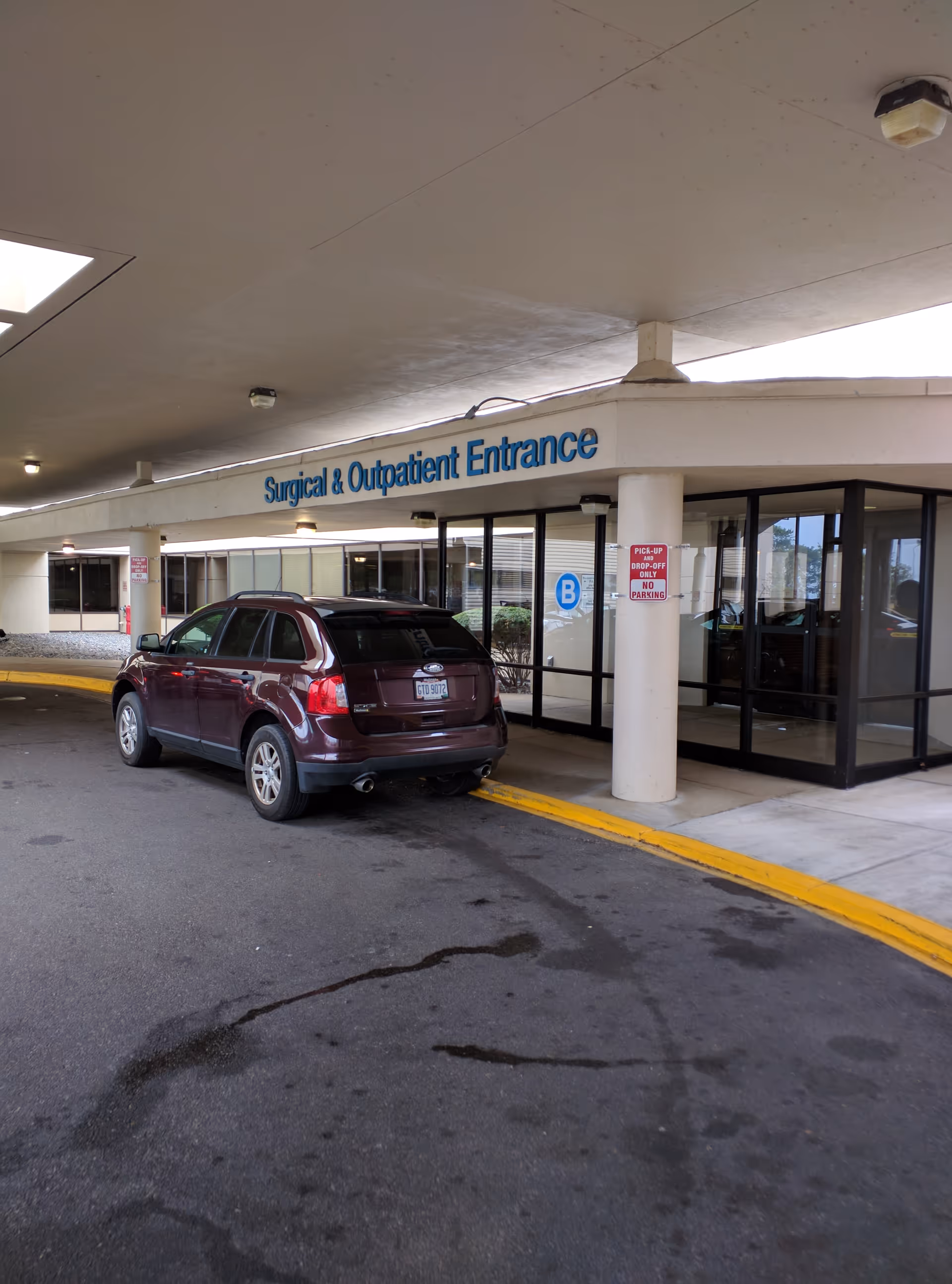 Exterior view of Mercy Health - Lorain Hospital entrance with a parked SUV