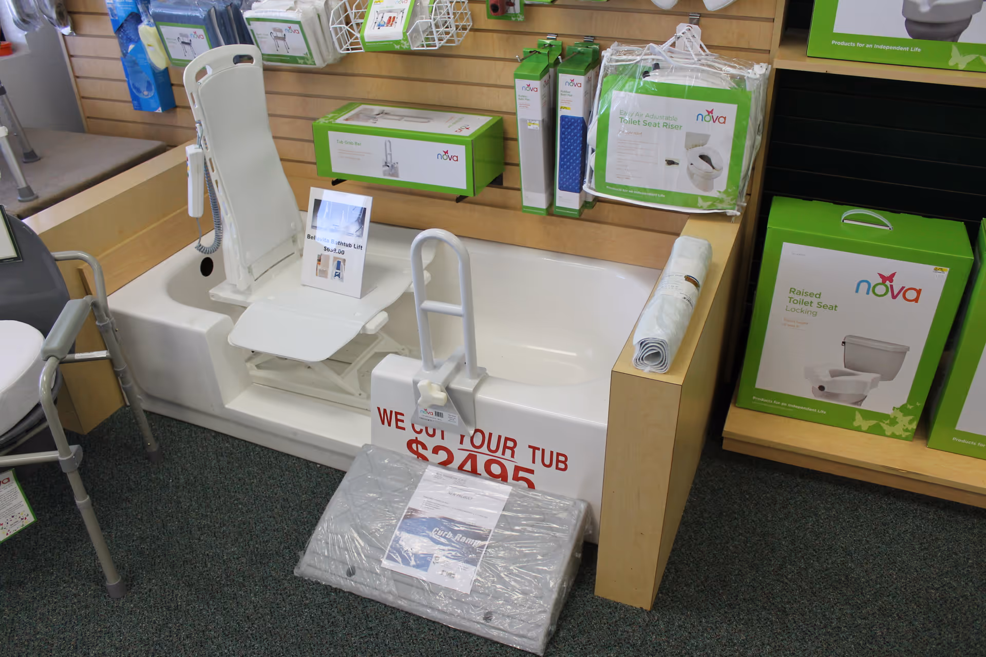 Showroom bathroom with tub lift, safety rail, and boxed Nova toilet seats on display.