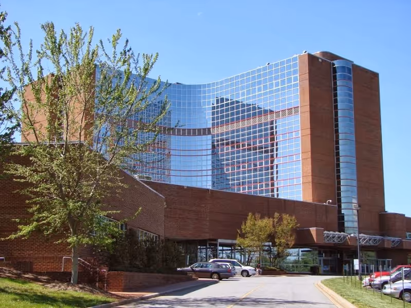 Exterior view of a modern brick and glass hospital building with parking lot.