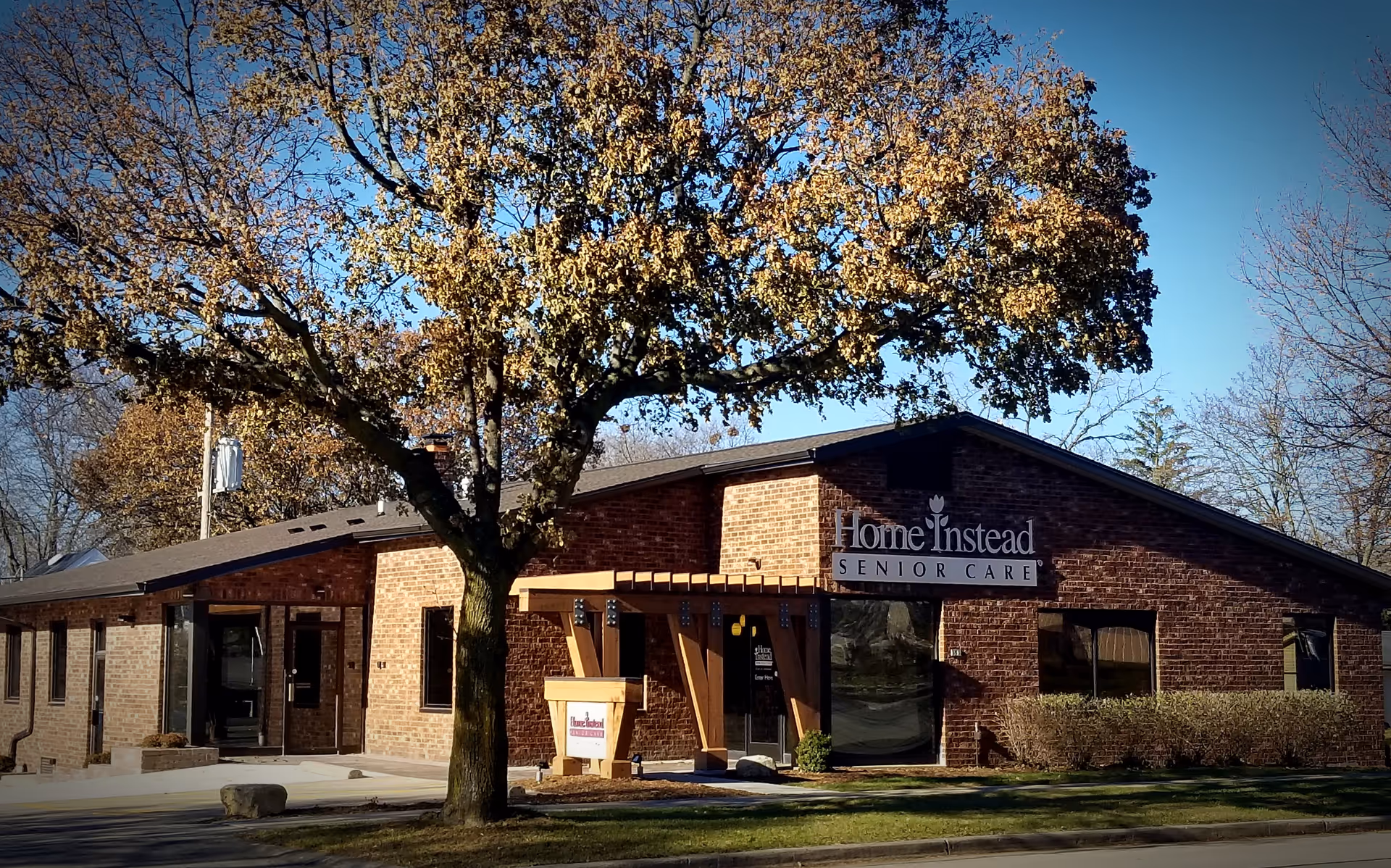 Brick senior care facility with a front entrance and Home Instead sign.