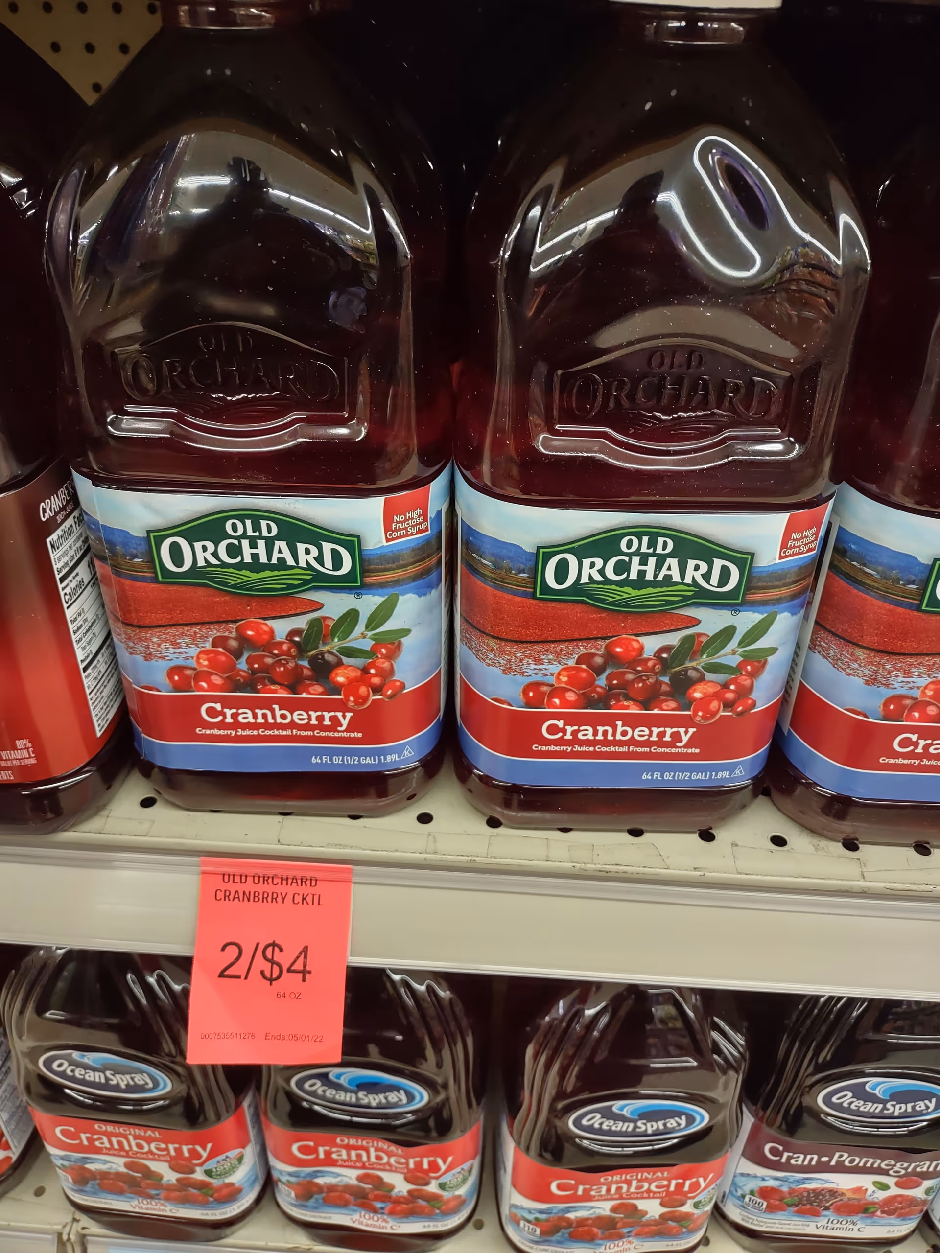 Rows of Old Orchard Cranberry juice bottles on a store shelf with sale tag.