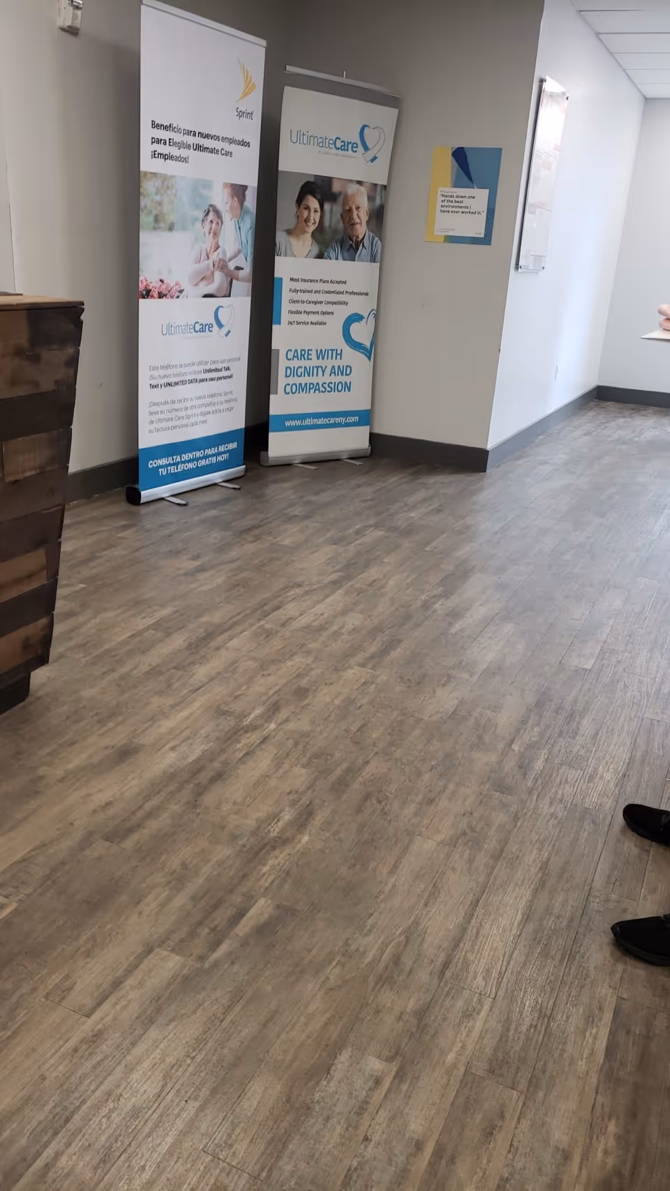 Indoor hallway in a senior facility with Ultimate Care banners displayed along the wall.