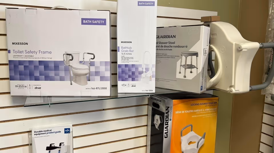 Shelf displaying boxed bath safety equipment and a wall-mounted lift device.