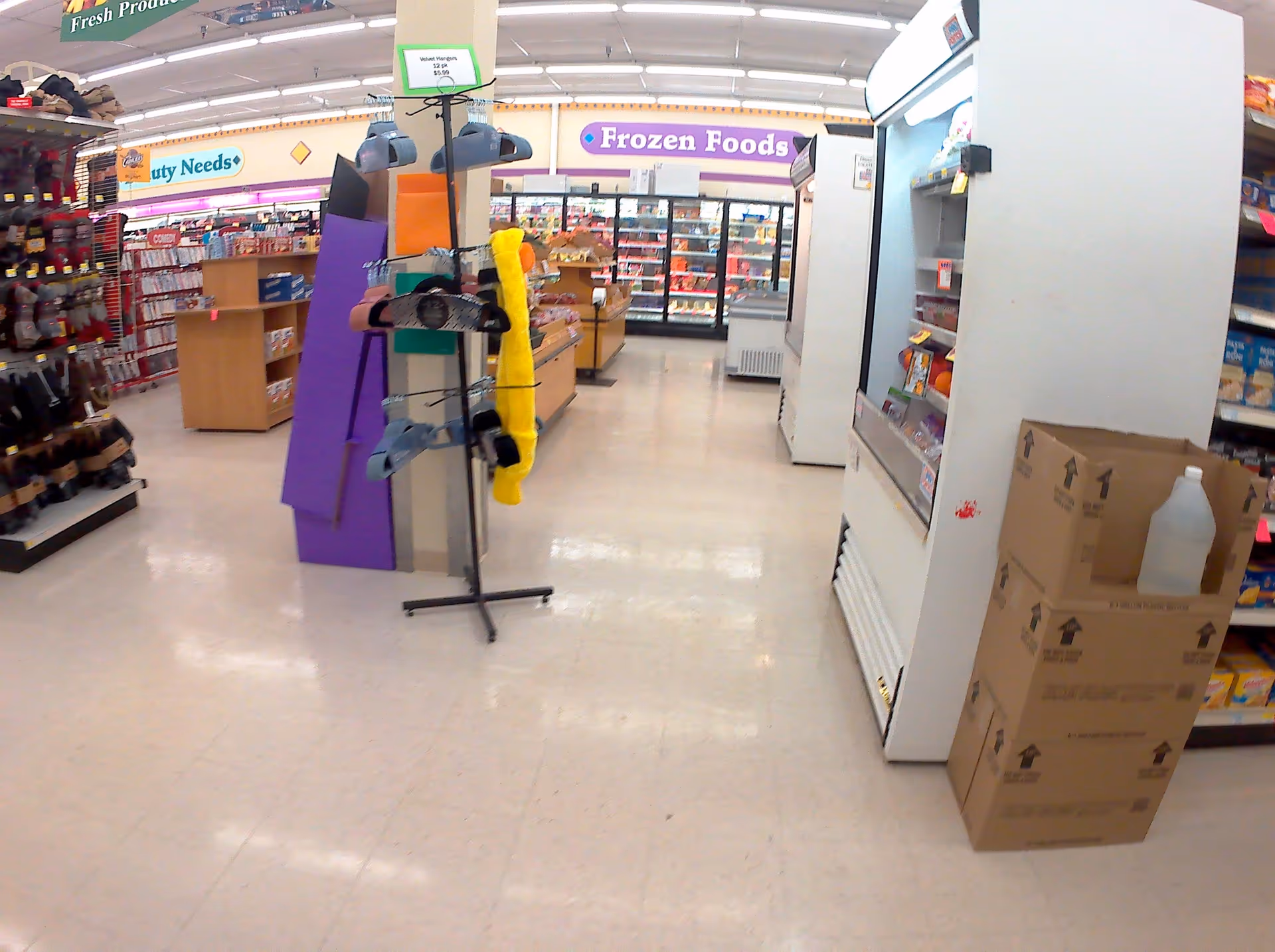 Wide store aisle inside Discount Drug Mart with frozen foods section and stacked cartons.