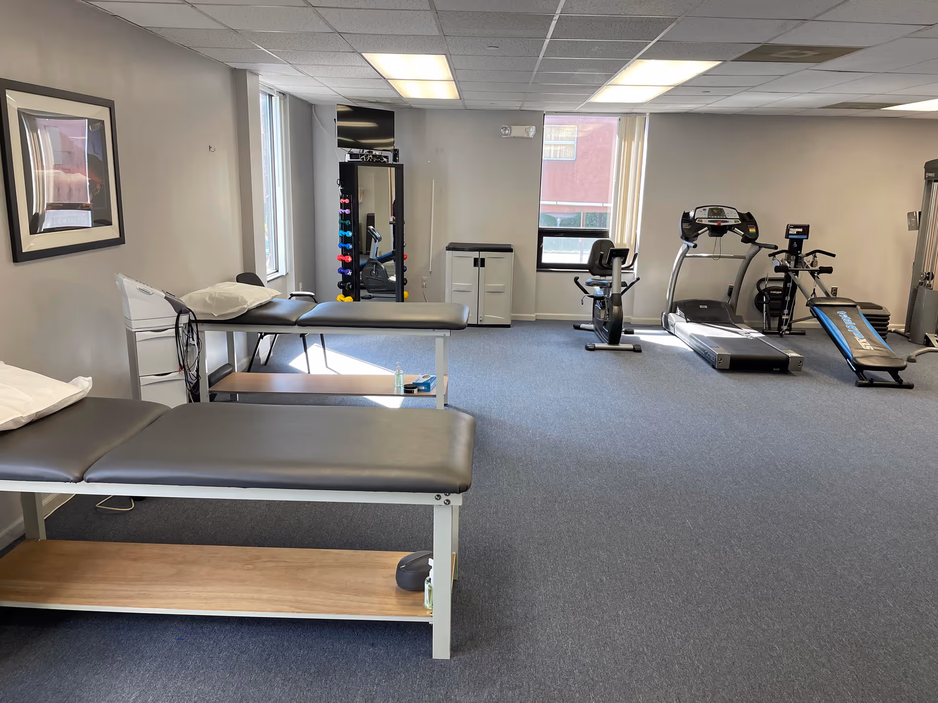Interior rehab gym at Rutherford Physical Therapy with therapy tables and cardio equipment.
