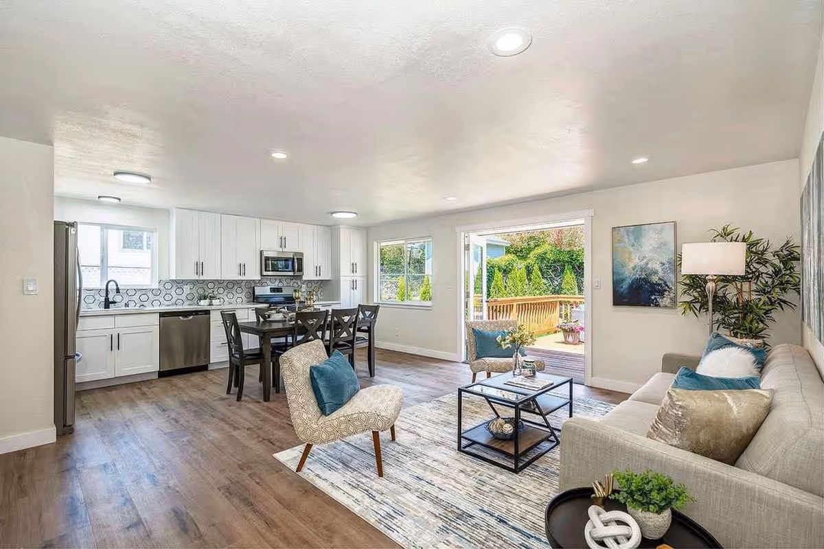 Open-concept living space with kitchen, dining area, seating, and a sliding door to a deck.