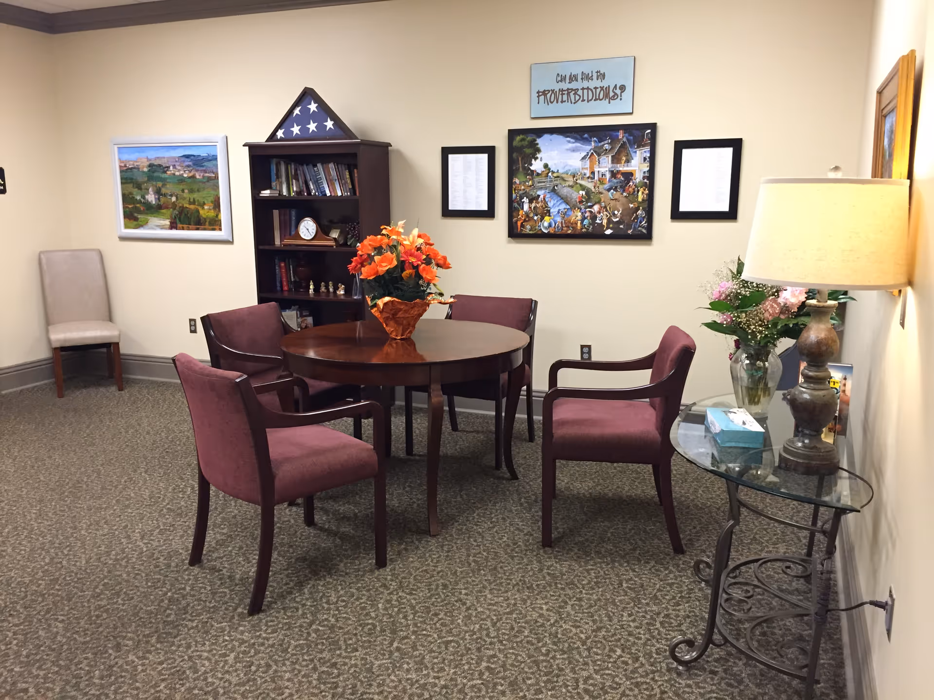A cozy interior lounge with a round table, purple chairs, and floral decor.