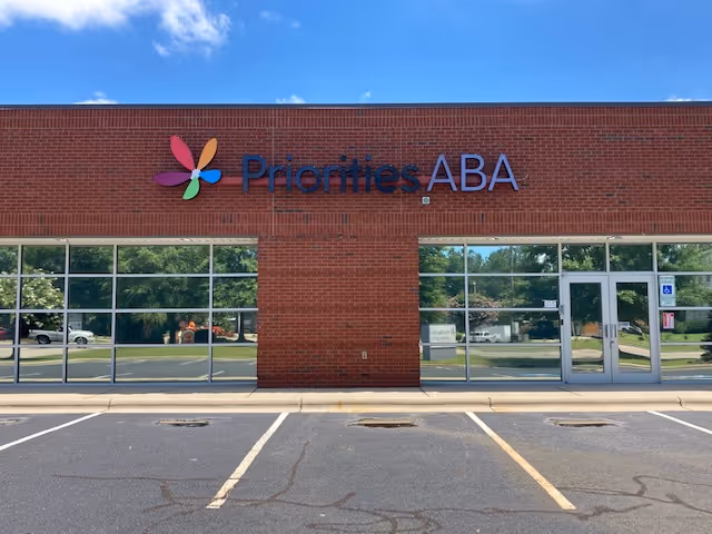Facade of a brick building with Priorities ABA sign and glass storefront doors.