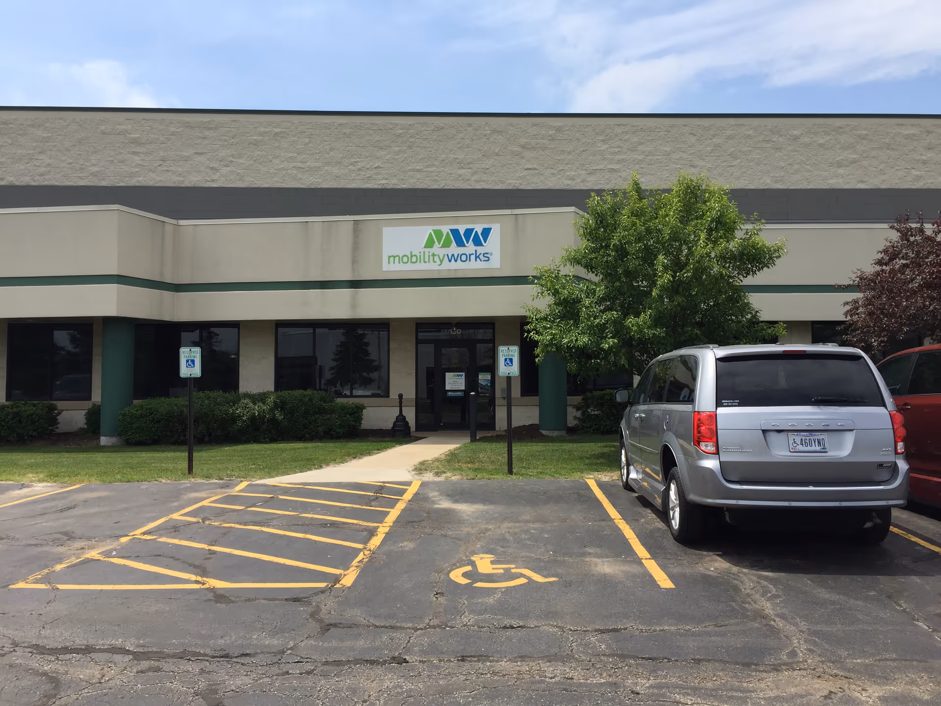 Front of MobilityWorks facility with parking lot and a silver minivan.