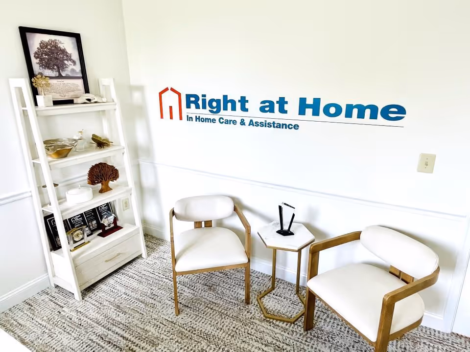 Waiting area with two white chairs, a small table, and Right at Home logo on wall.