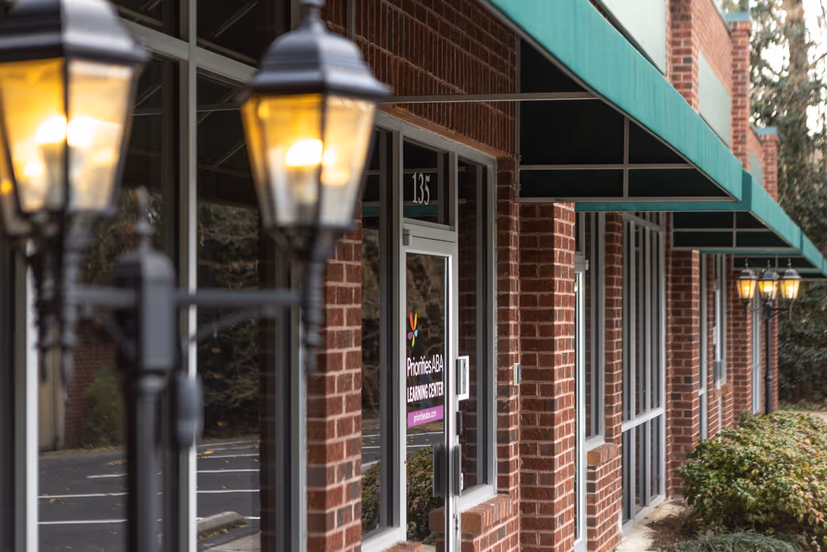 Brick exterior of Priorities ABA Learning Center with glass doors and green awnings