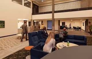 A spacious interior lobby with blue sofas, tables, and residents chatting with staff.