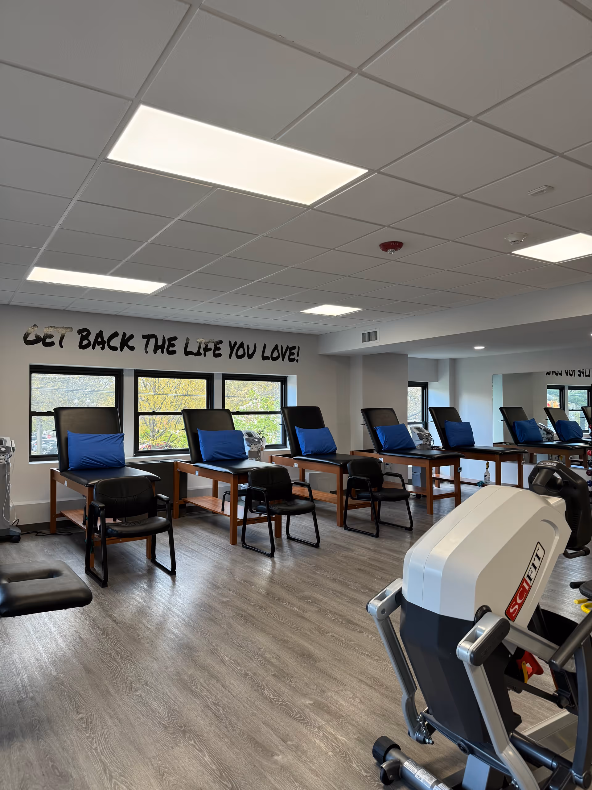Well-lit interior therapy room with treatment chairs, exercise equipment, and motivational wall text.