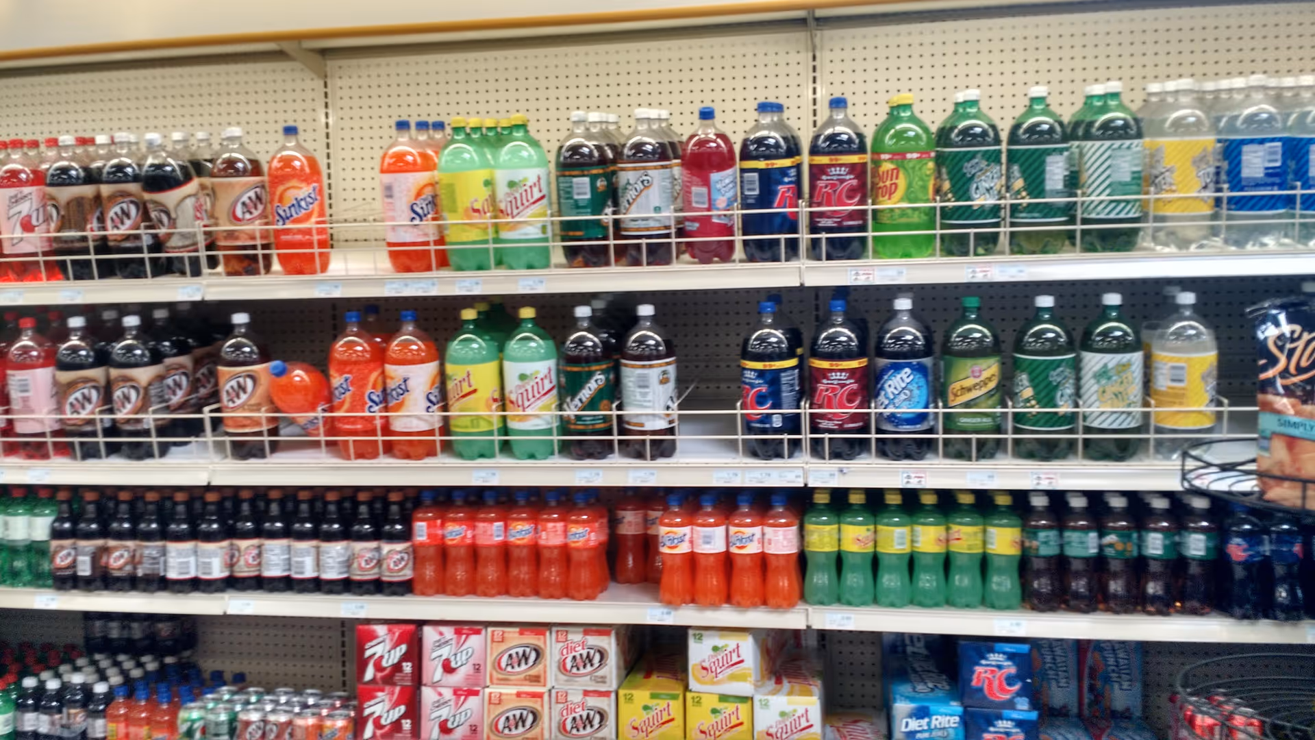 Aisle of bottled beverages on store shelves at Discount Drug Mart.