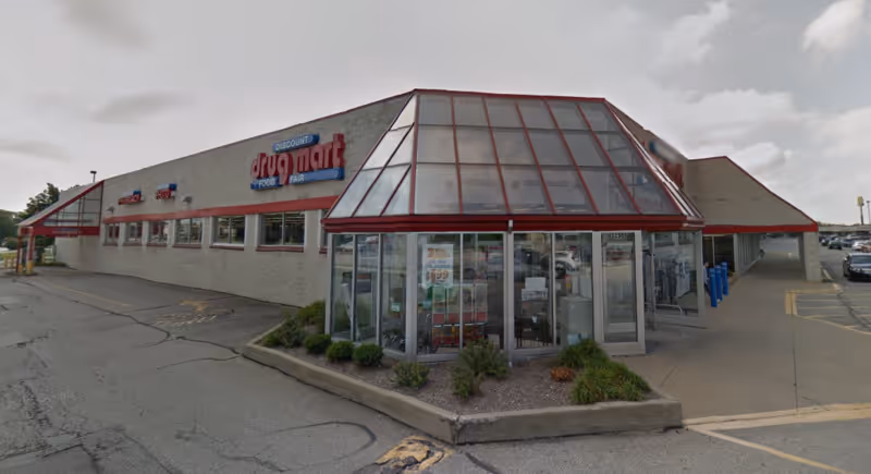 Exterior view of a Discount Drug Mart storefront with glass entry and parking lot.