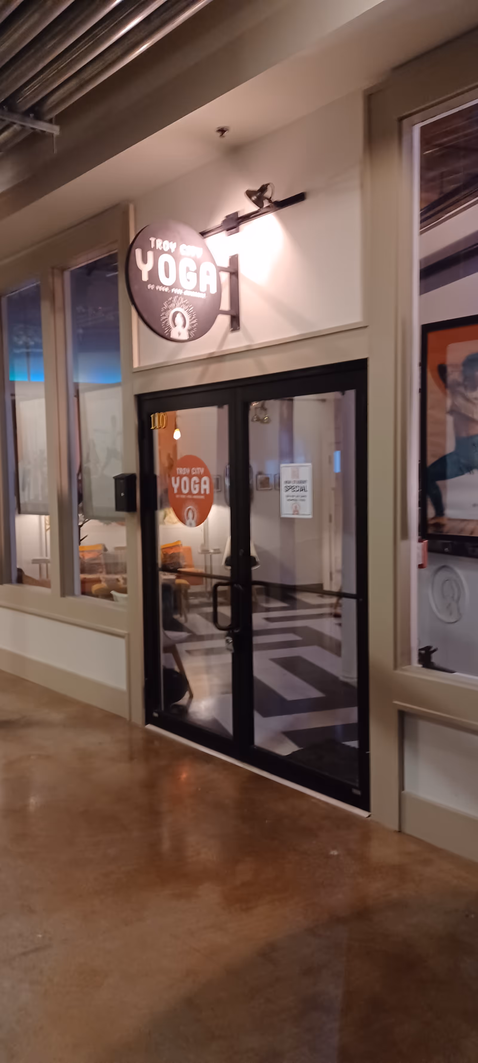Indoor corridor showing a yoga studio entrance with a Yoga sign.