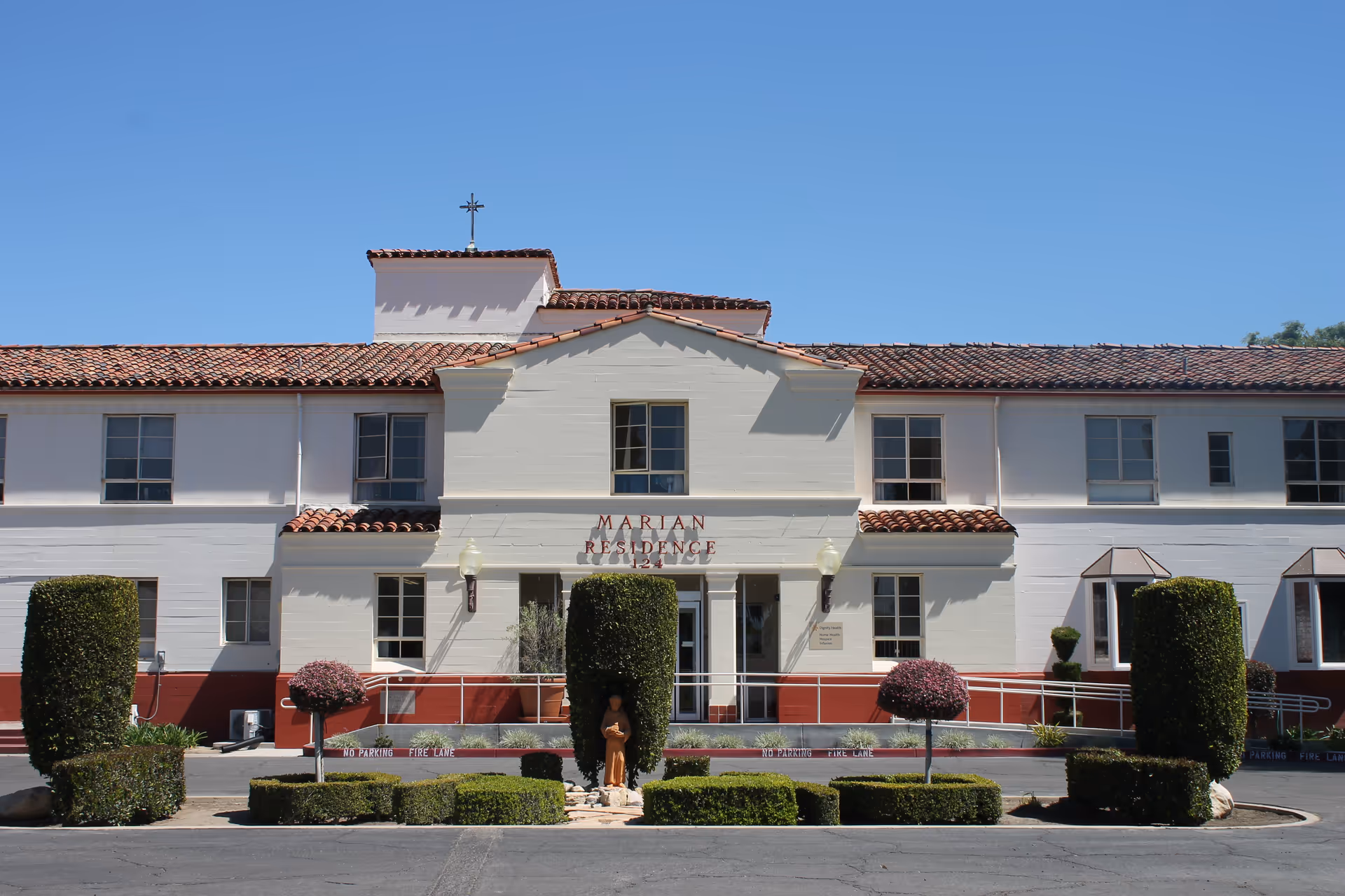 Front exterior of Marian Residence senior living facility with white walls and red-tiled roof.