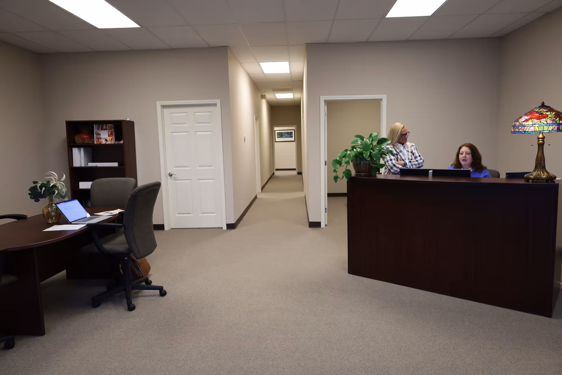 Reception desk with two staff members in a hallway of a senior facility