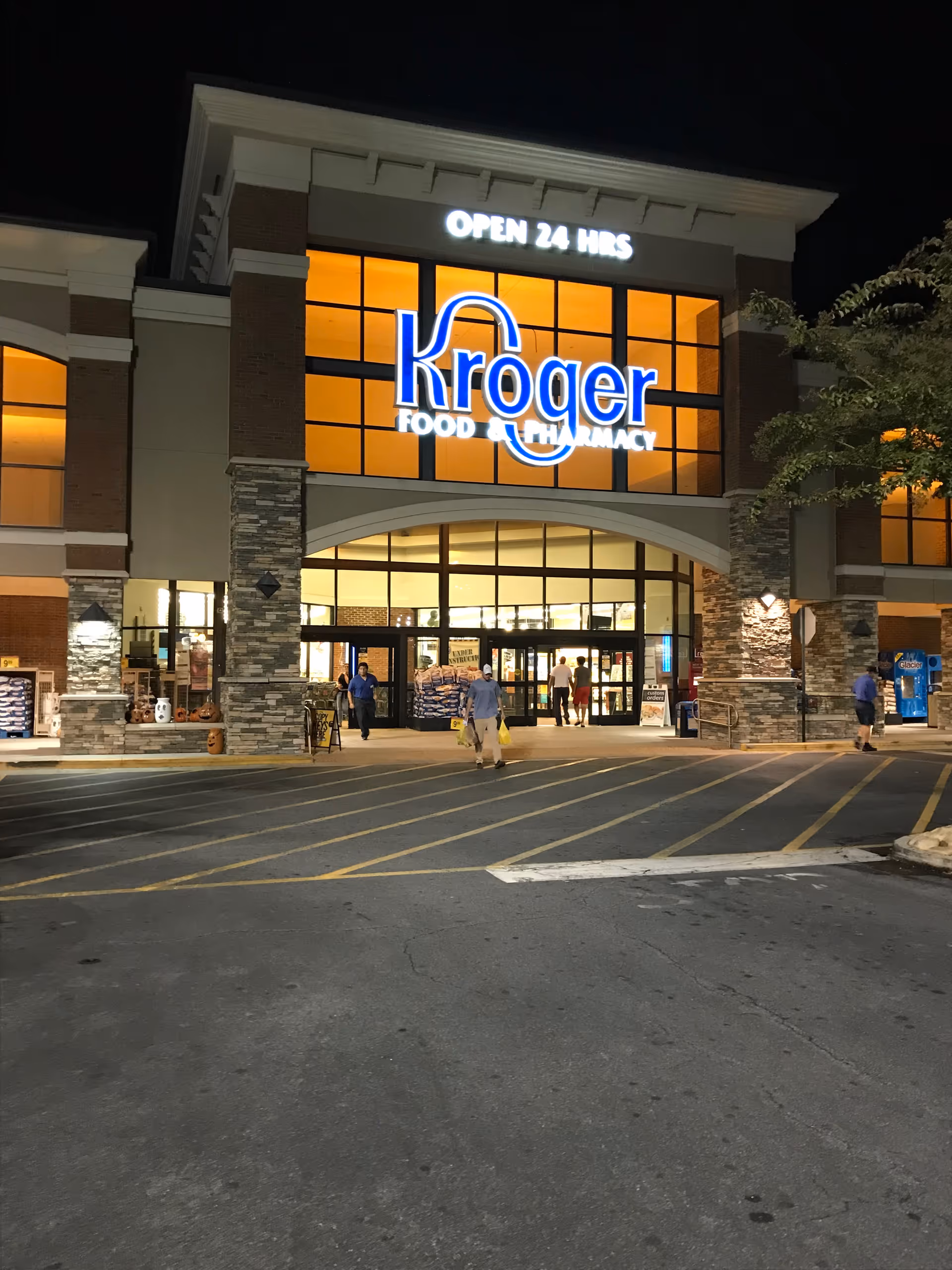Night exterior of Kroger store with open entrance and illuminated sign.