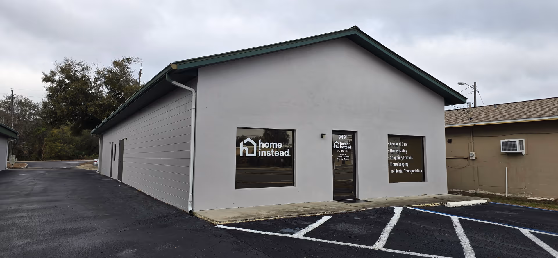 Front view of a light gray building with Home Instead signage and a parking lot.