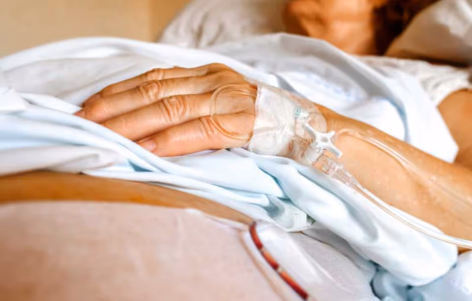 Close-up of a patient's hand with an IV line in a hospital bed