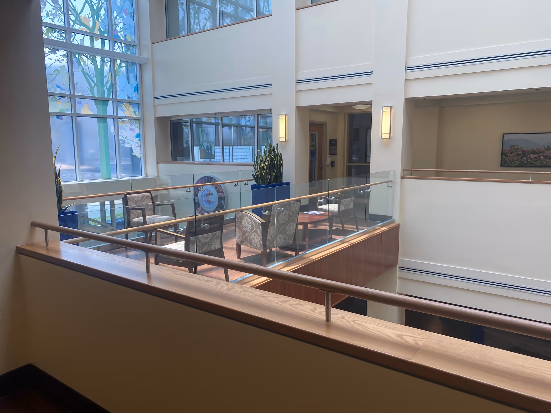Bright interior atrium with glass railing, seating area, and large windows