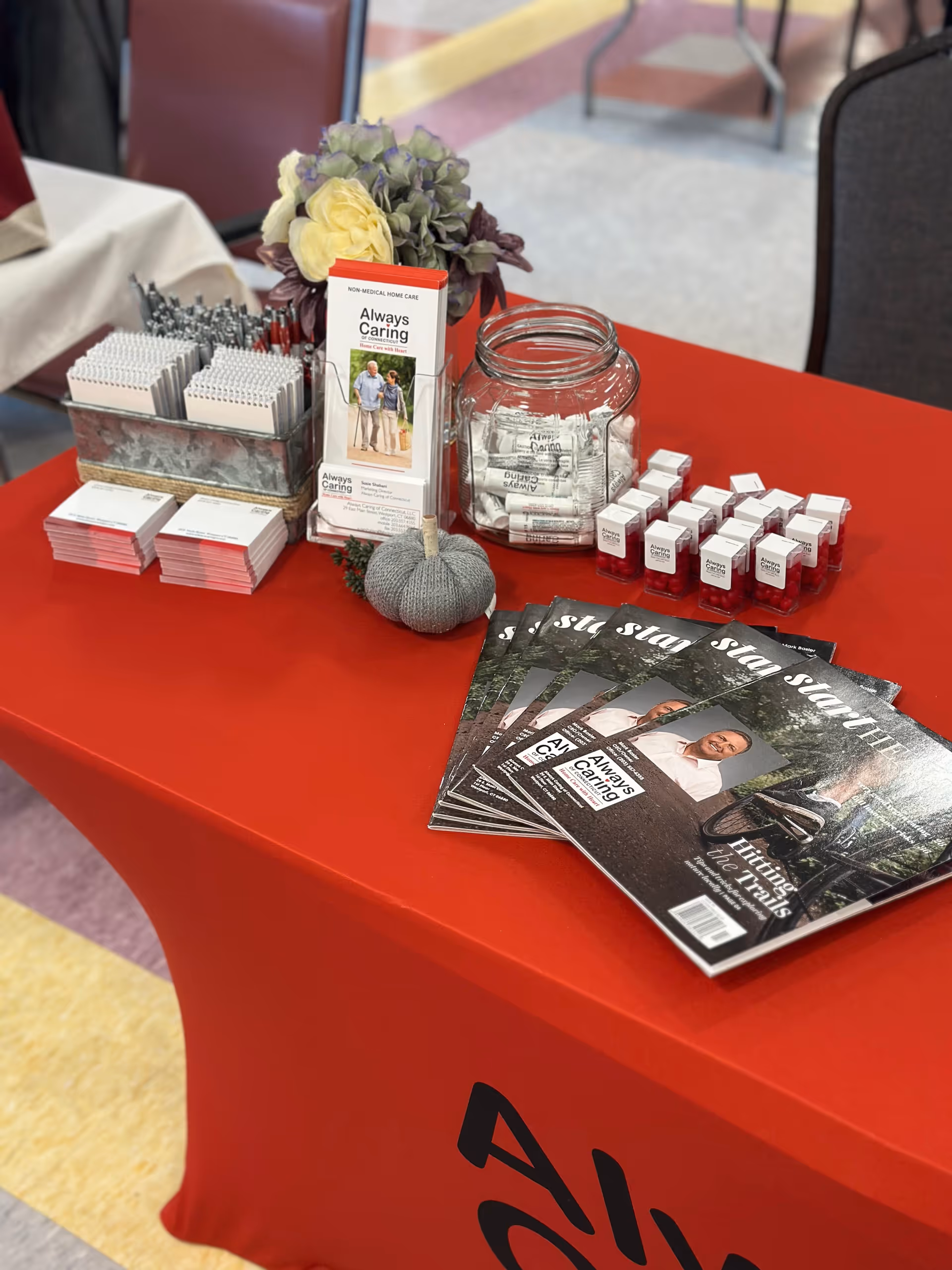 Promotional table with Always Caring brochures, a glass jar, and display items indoors.