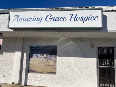 Front exterior of a white building displaying an Amazing Grace Hospice sign.