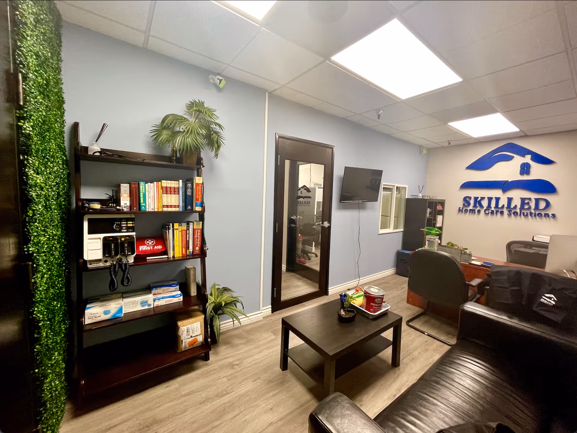 Reception area with desk, seating, bookshelf, and the facility logo on the wall.