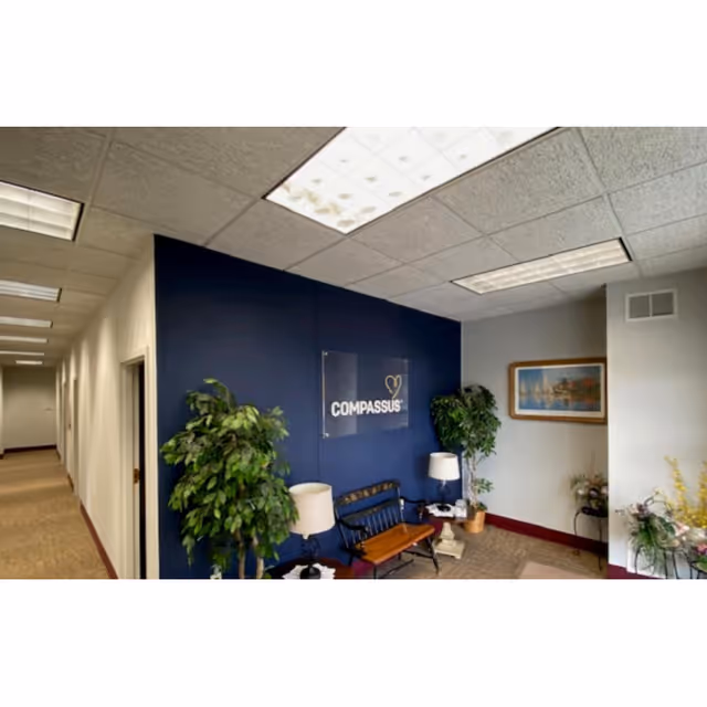 Interior hallway and reception seating area with a Compassus sign on a blue wall.