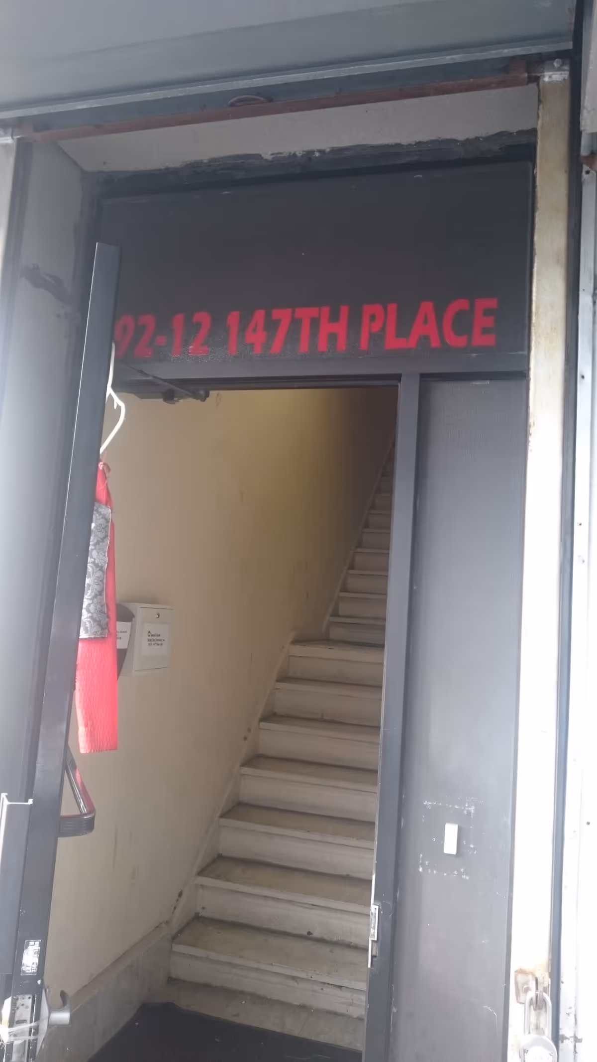 Open doorway to a stairwell inside with a red address sign visible