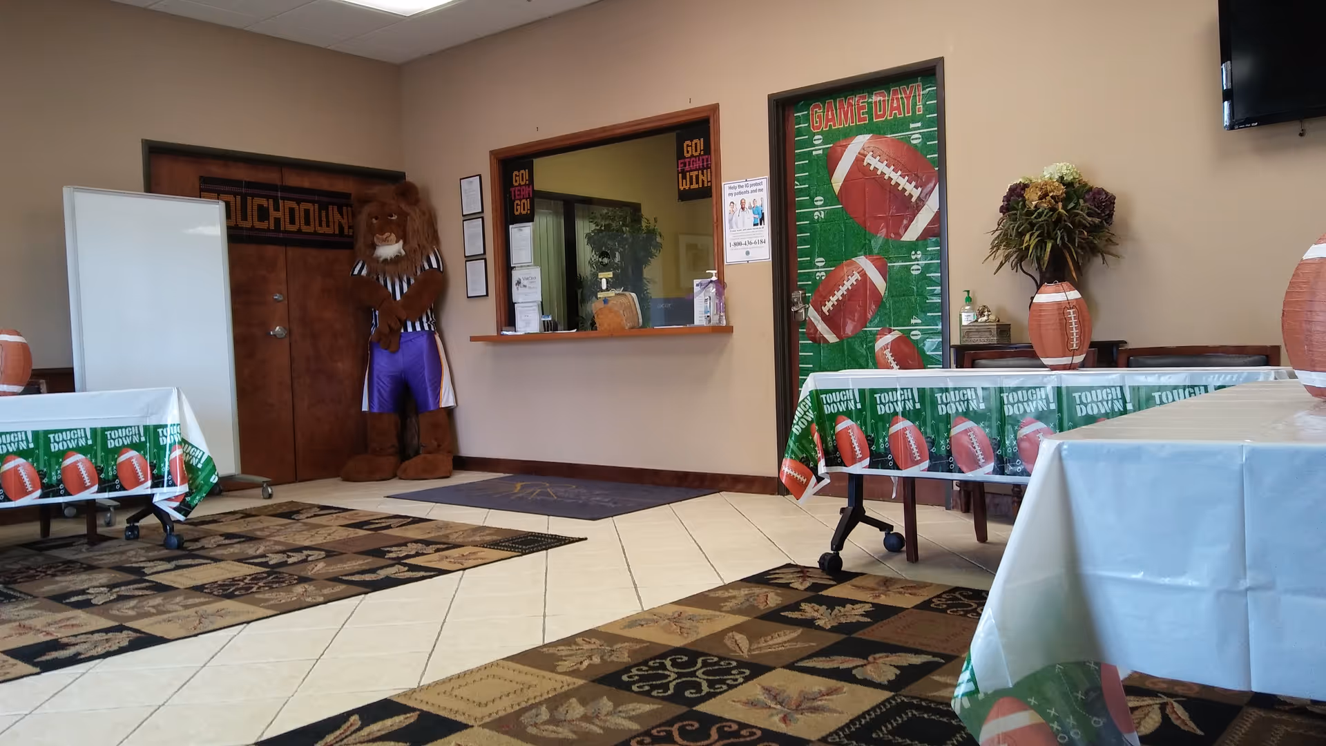 Interior reception area decorated for game day with a lion mascot and football-themed tables.