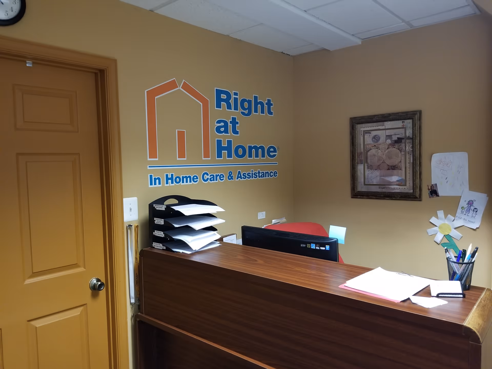 Reception area of Right at Home office featuring logo on wall and a desk.
