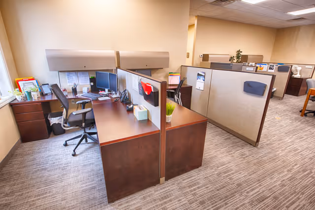 Open office area with cubicles, desks, and computer workstations in a staff workspace.