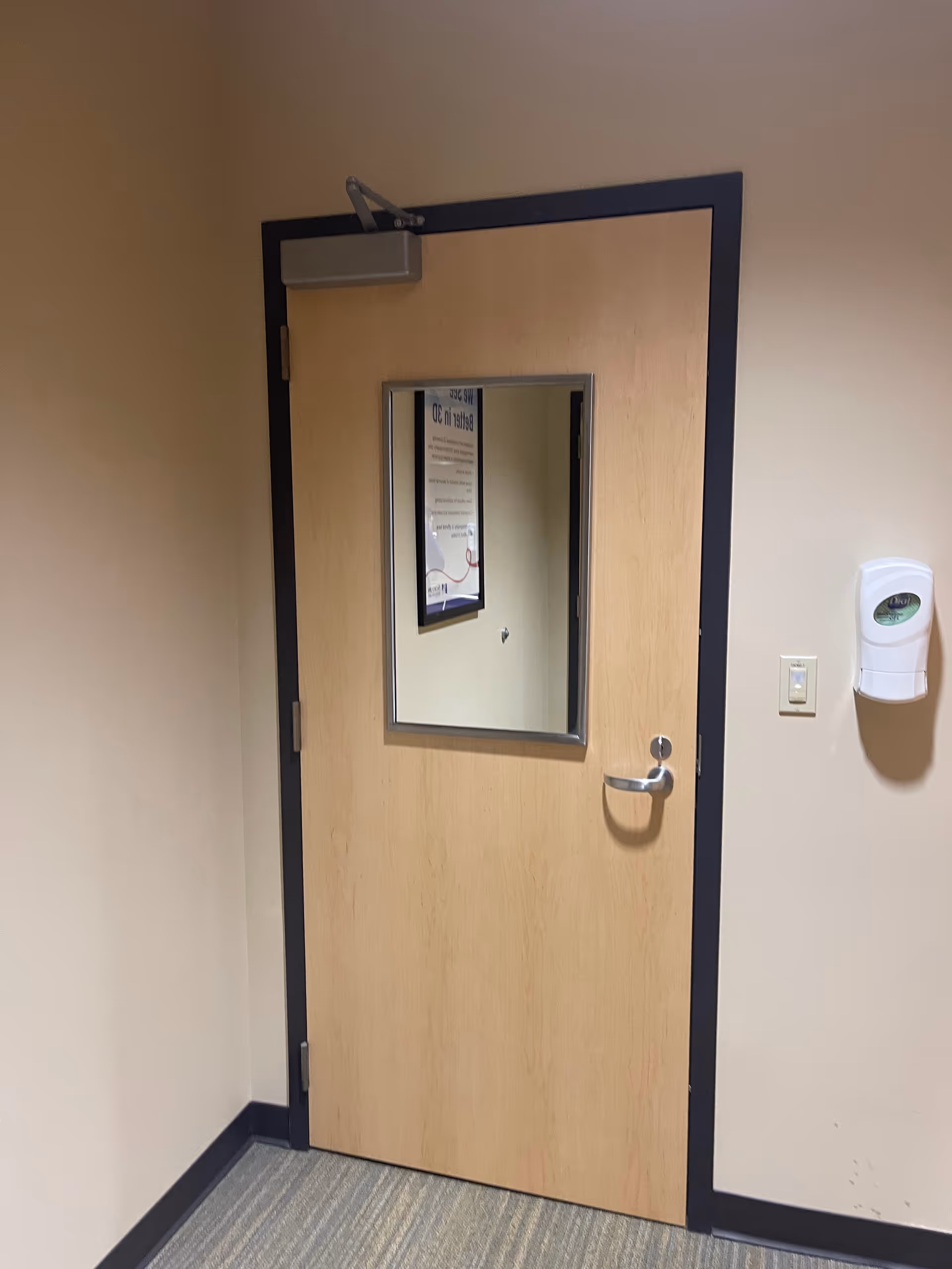 Wooden interior door with a small window in a beige hallway.