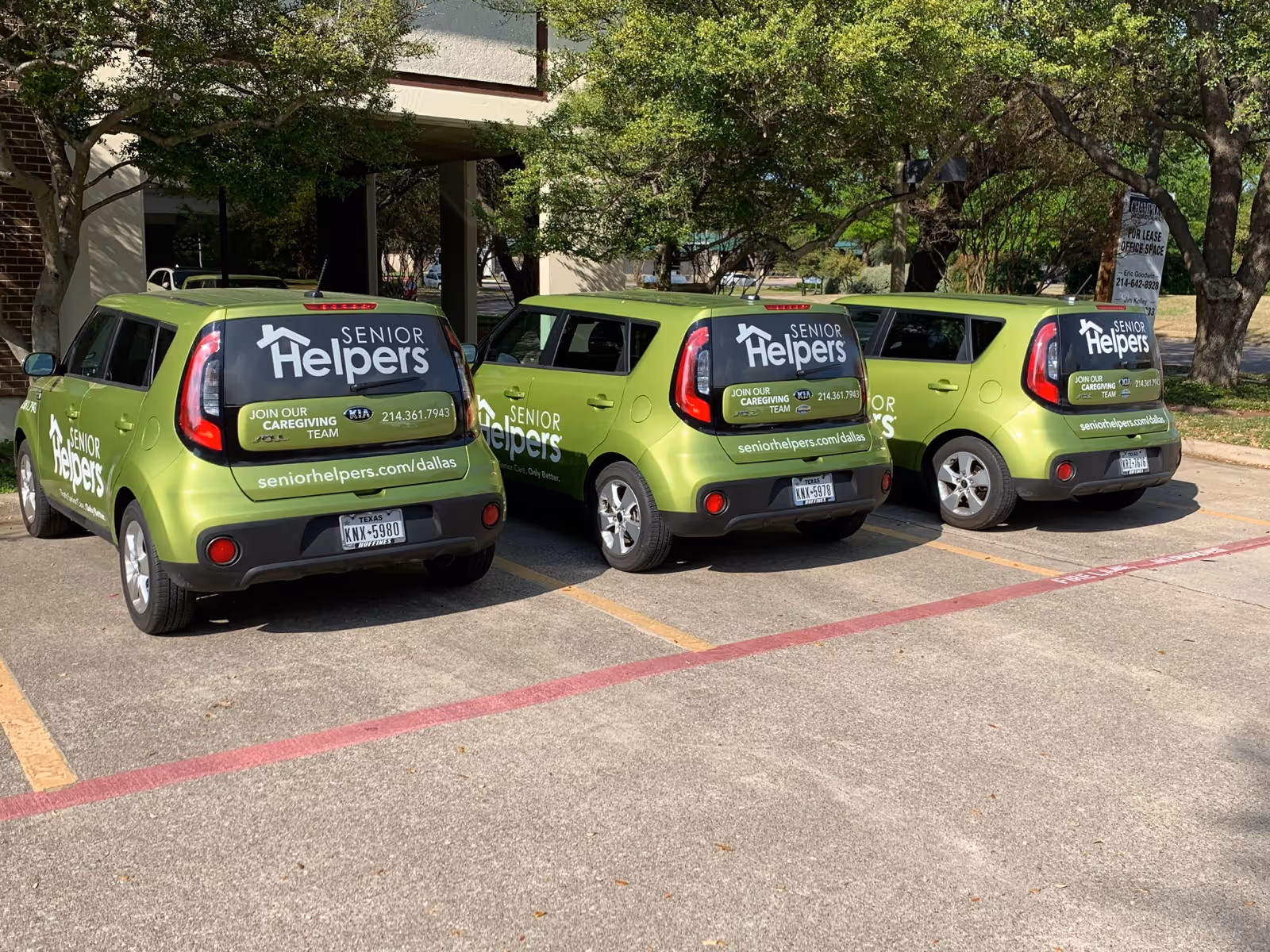 Three lime-green Senior Helpers cars parked in a lot near a building.
