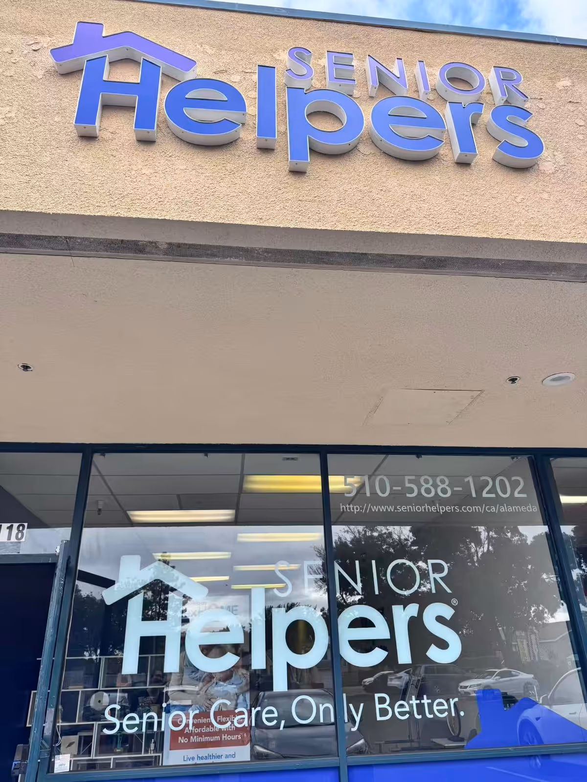 Exterior view of a Senior Helpers storefront with a large purple sign on beige facade.