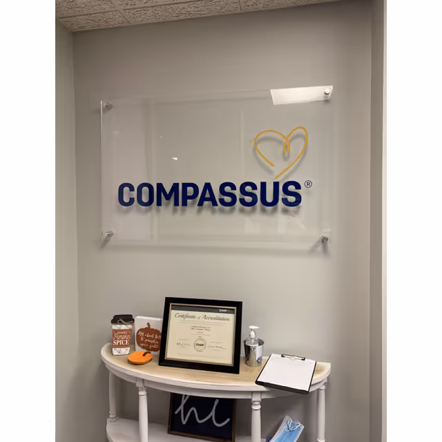 Interior hallway featuring a Compassus sign on the wall and a small reception table.