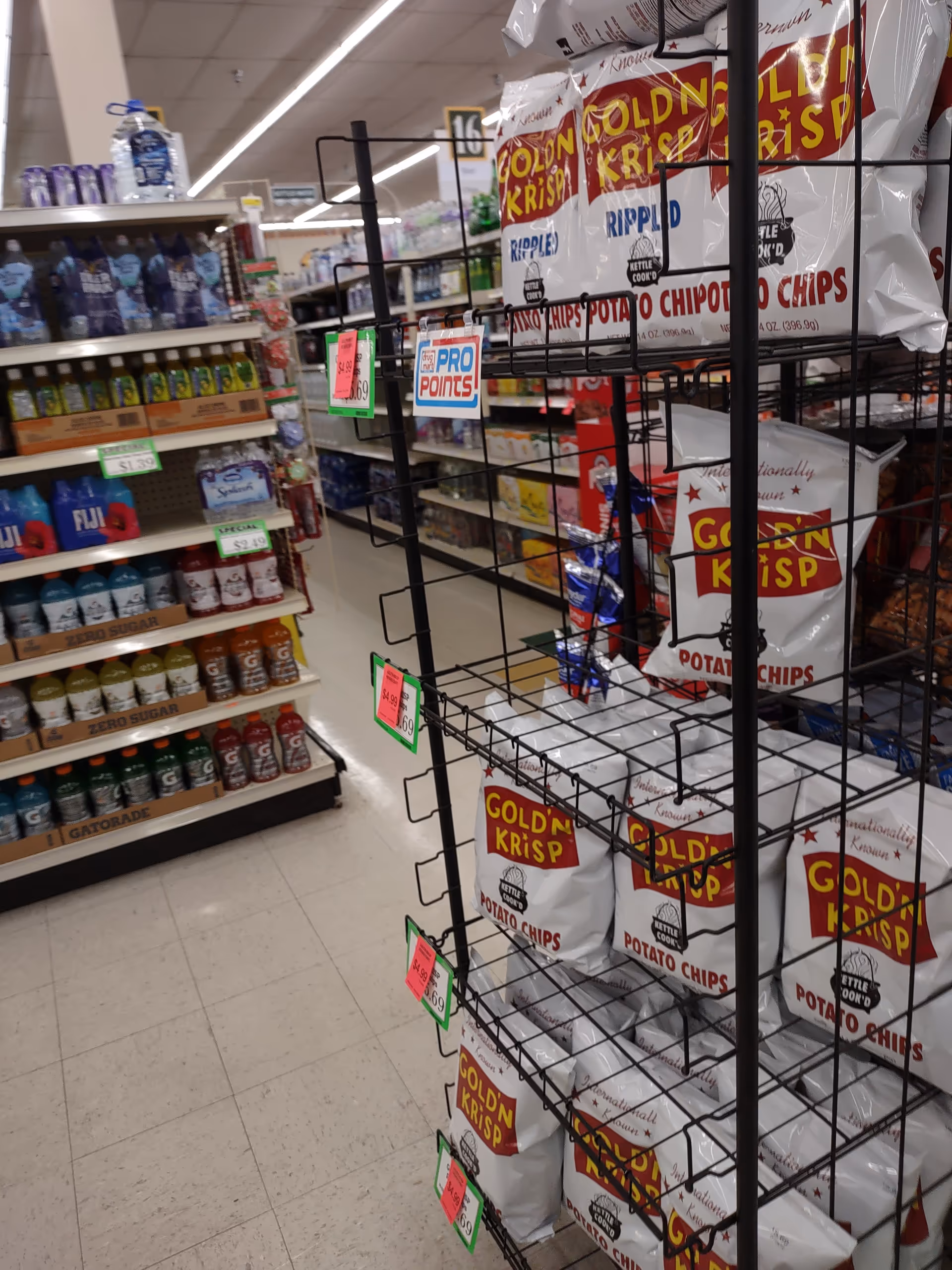 Inside Discount Drug Mart, a store aisle with chips on racks and beverage shelves.