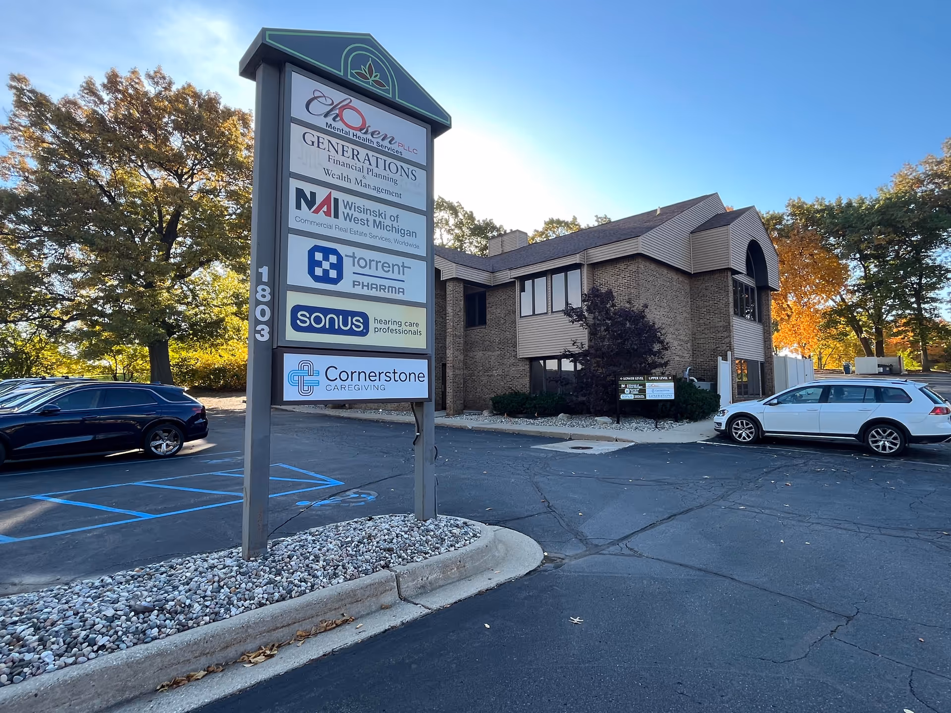 Exterior view of brick building with a tall sign listing Cornerstone Caregiving in parking lot.