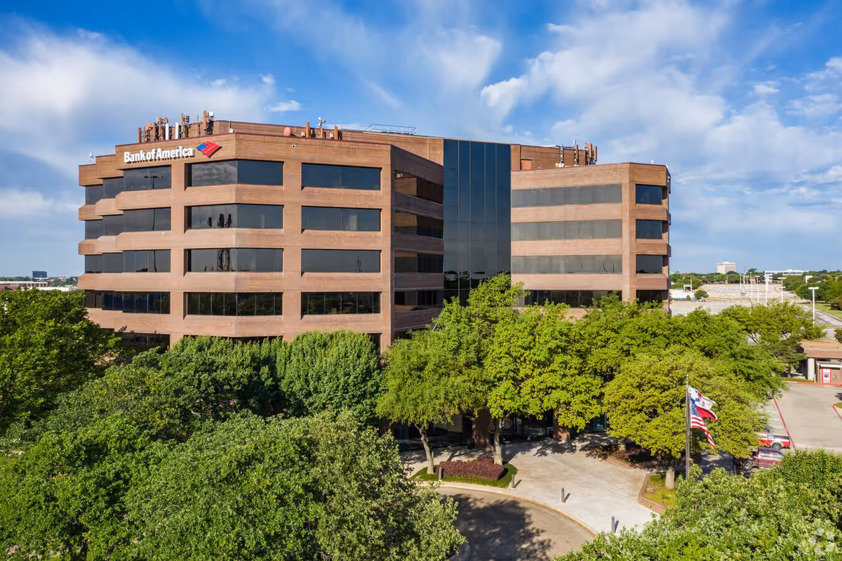 Exterior view of a brick Bank of America building with surrounding trees.